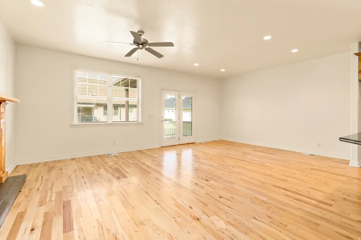 Hardwood flooring, recessed lighting, ceiling fan, French doors, and a fireplace with wood mantel