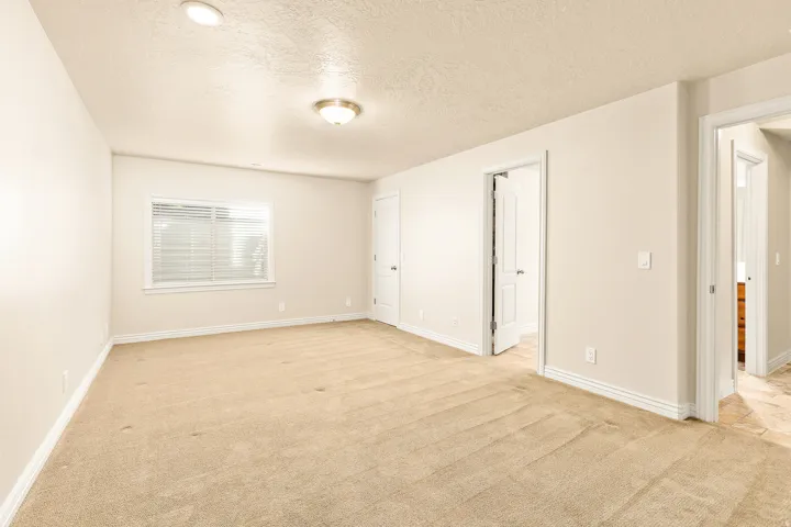Wall-to-wall carpeting in a neutral tone, recessed ceiling lighting, and a window with horizontal blinds