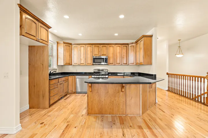 Kitchen featuring wood cabinetry, stainless steel appliances, dark countertops, and a central island