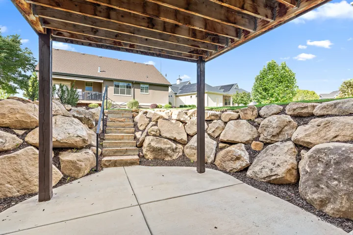 Concrete patio with an exposed wood ceiling, flanked by natural stone retaining walls