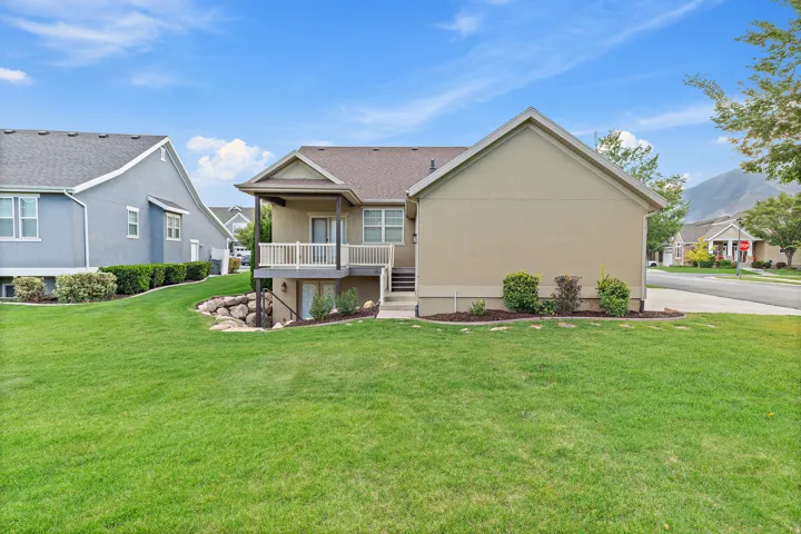 Spacious lawn area with mature landscaping, covered upper-level deck, and walk-out lower-level access