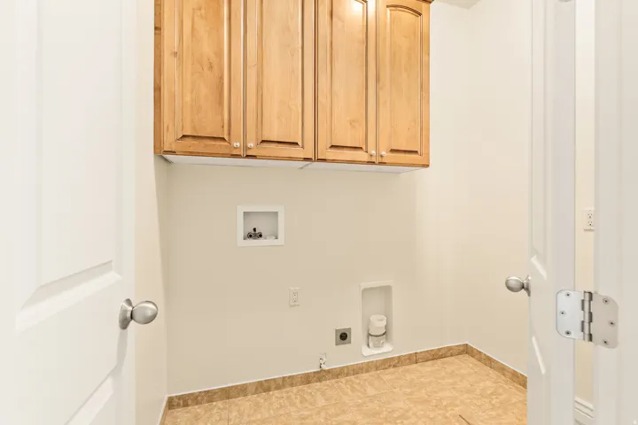 Laundry area featuring wood cabinetry, tile flooring, and utility hookups