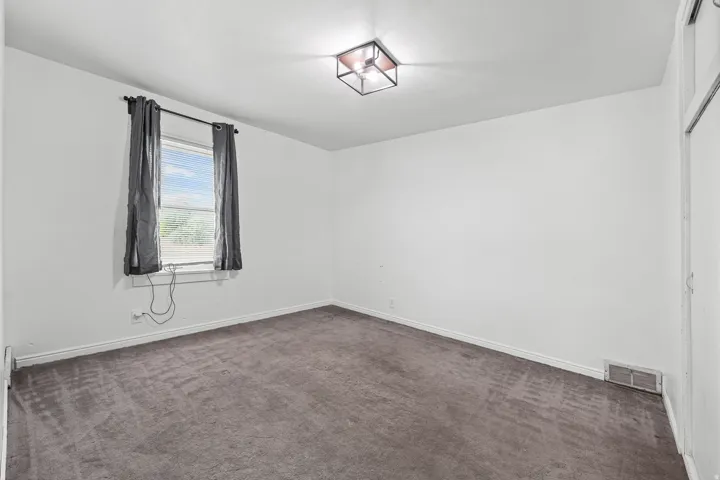 Bedroom – A comfortable carpeted bedroom featuring a curtained window that invites in soft natural light.