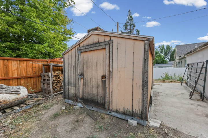 Freestanding wood-panel shed with a pitched roof, featuring a solid wood door