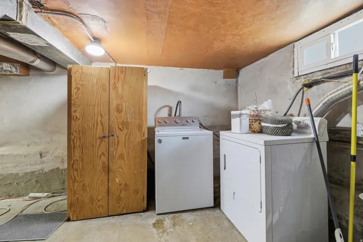 Laundry Area – A functional unfinished laundry space equipped with washer and dryer hookups and a built-in wood storage cabinet.