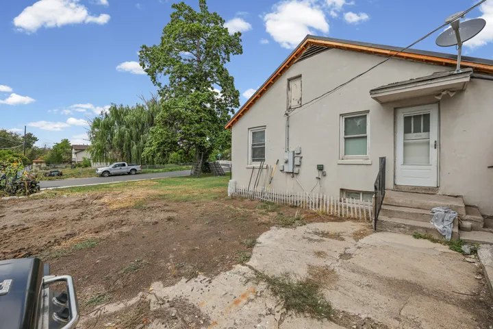 Rear exterior with stucco siding, an attached concrete patio, and a white entry door with a storm door