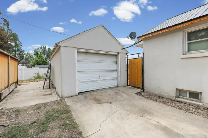 Detached garage with a paneled door, concrete driveway, and a wood privacy fence