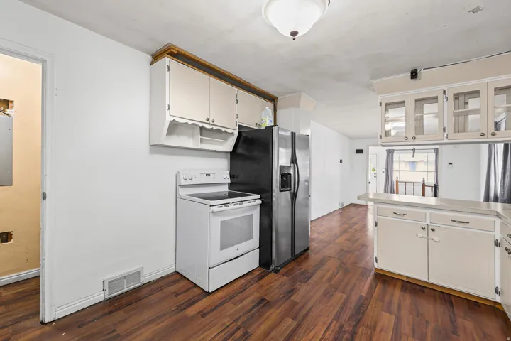 Kitchen (additional view) – Ample cabinet storage surrounds the stainless-and-black refrigerator, with a pass-through counter opening to the adjacent dining space.
