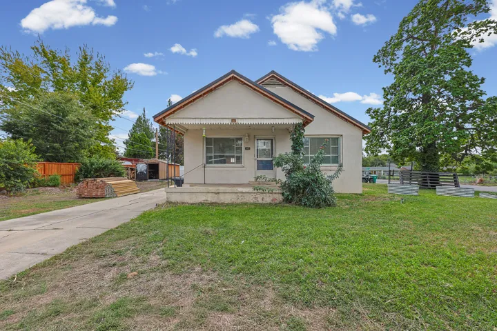 Front Exterior – Welcoming front exterior with a covered porch, mature landscaping, and a spacious grassy yard. The classic gabled roofline and charming porch details add character to the home.