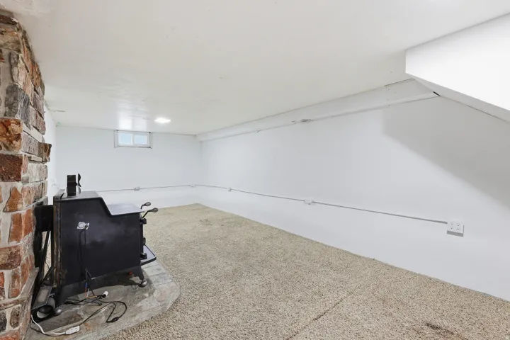 Basement Recreation Space – A large, versatile basement area highlighted by a stone accent wall and freestanding wood-burning stove, ready to serve as a family room, game room, or flex space.