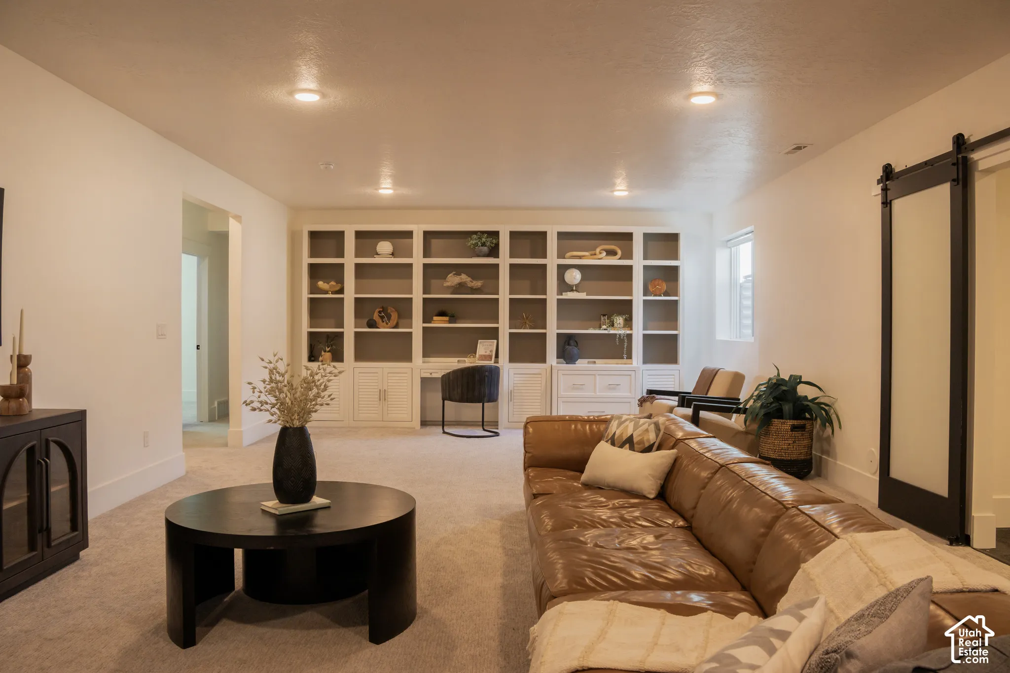 Recessed lighting, built-in shelving with desk space, and a barn door with frosted glass panel