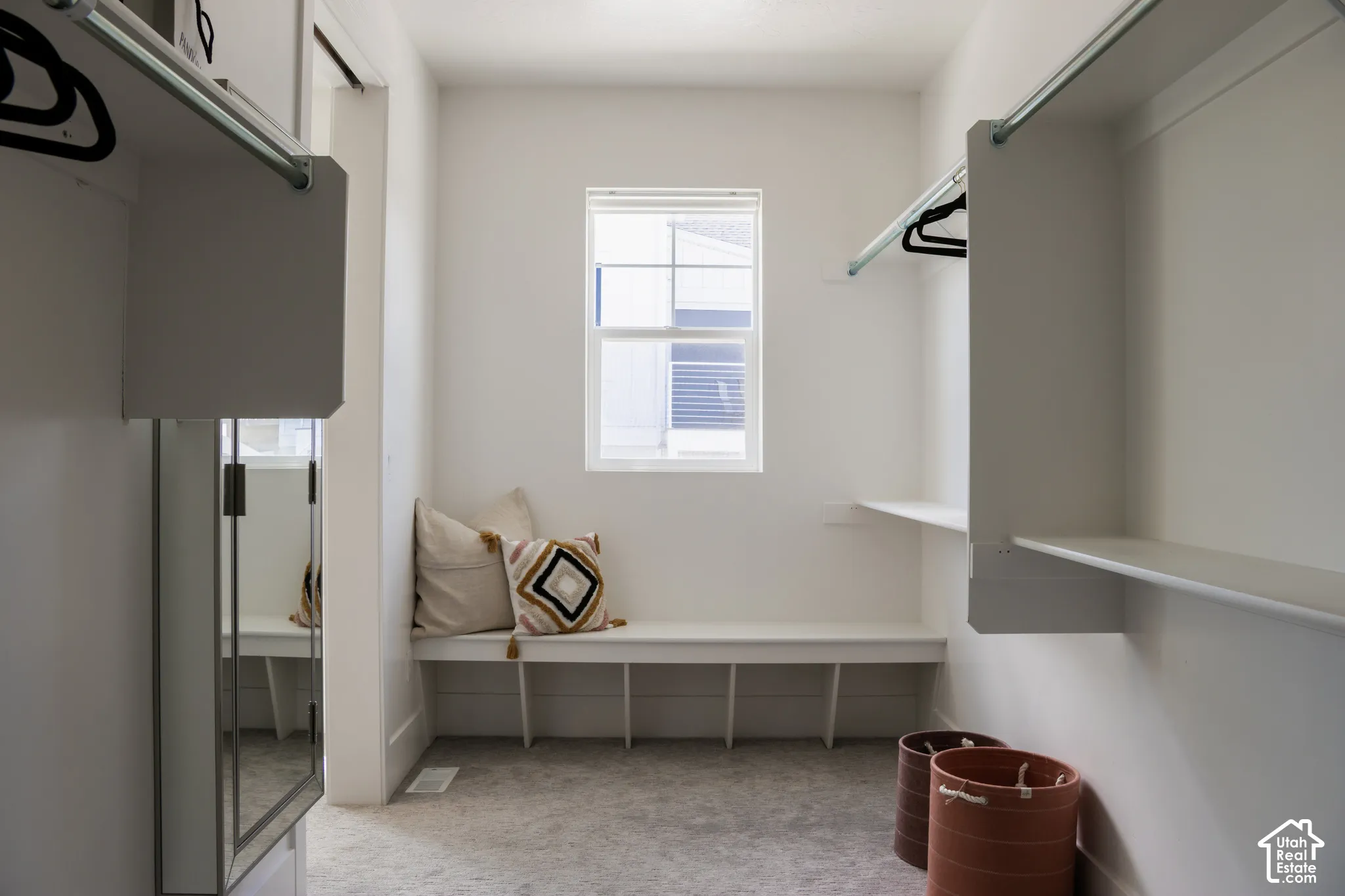 Recessed window, built-in bench with integrated shelving, white built-in shelving, and hanging rods