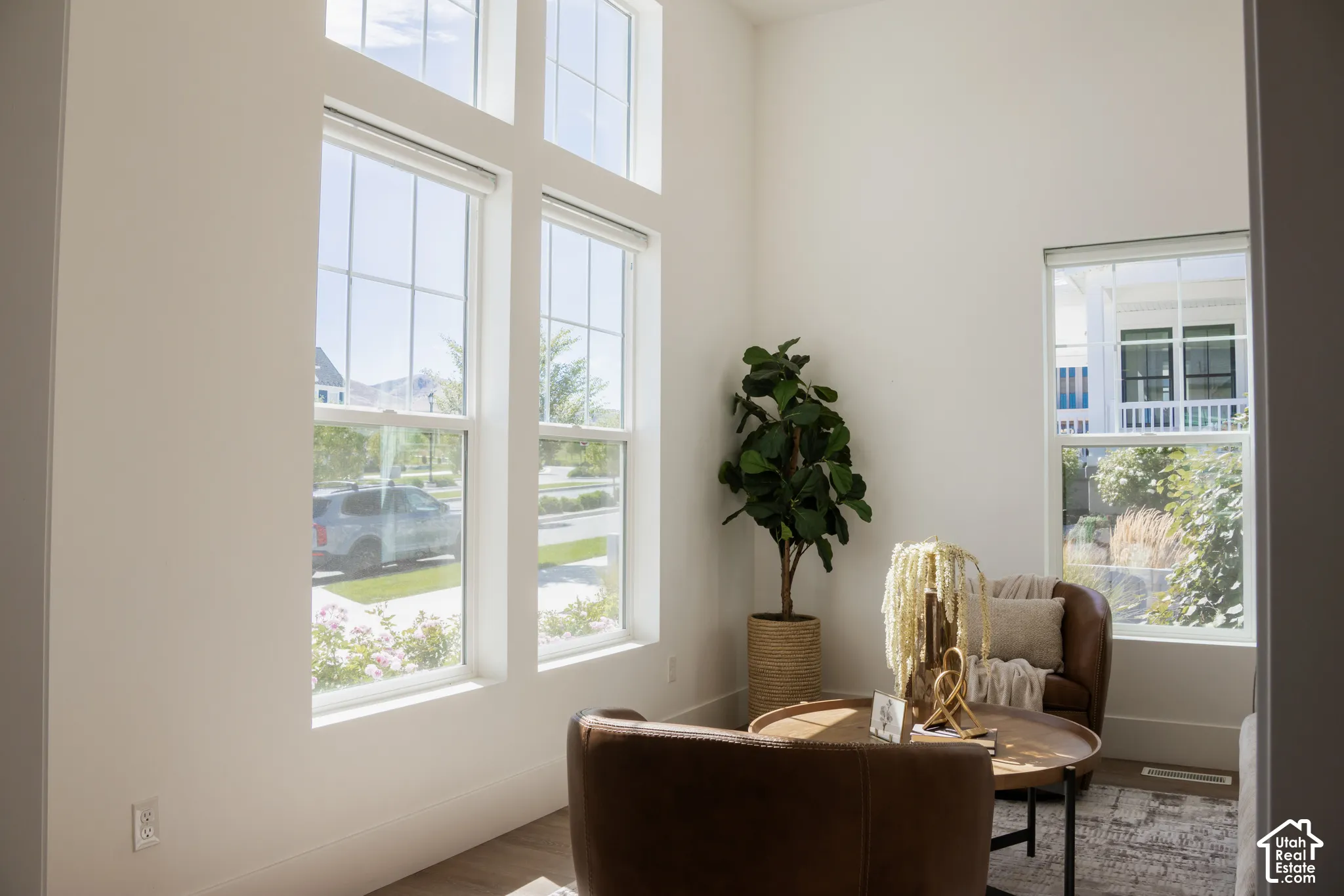 Soaring ceilings with transom windows, expansive white walls, wood-finish flooring, and large picture windows