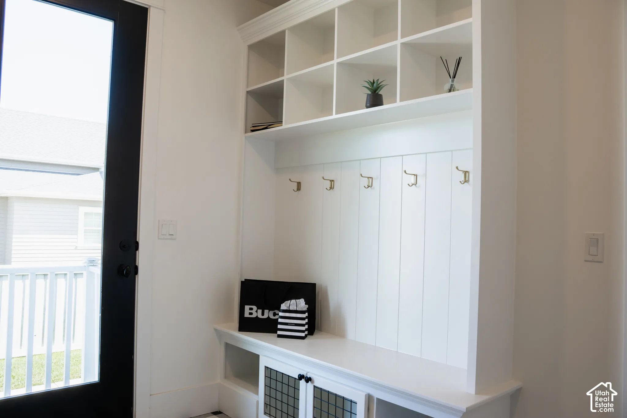Built-in storage unit featuring open shelving, coat hooks, and lower cabinetry with glass panel inserts