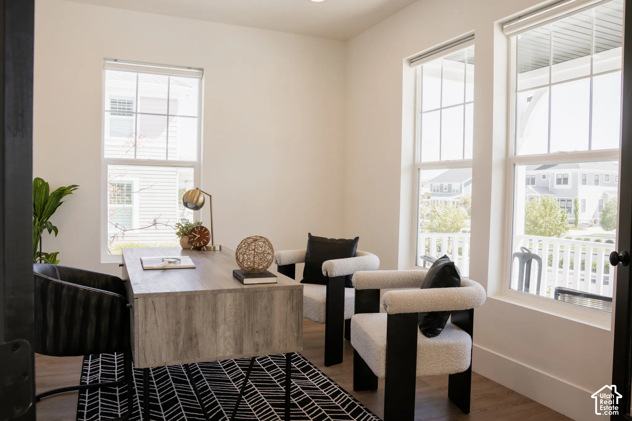 Bright interior featuring three large windows, white walls, and wood-finish flooring