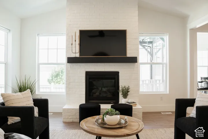 Vaulted ceilings complemented by a white brick fireplace with a black mantel and integrated firebox