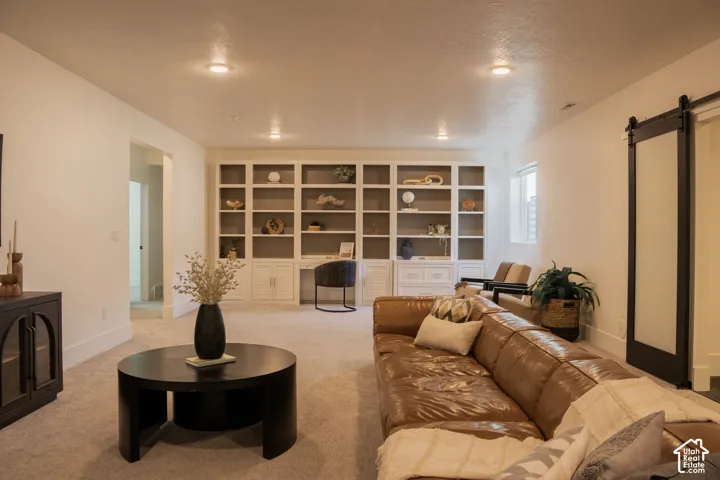 Recessed lighting, built-in shelving with desk space, and a barn door with frosted glass panel