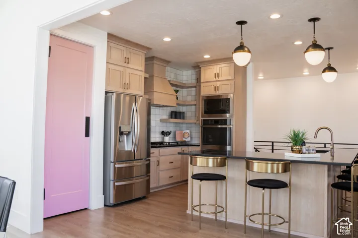Kitchen featuring a built-in oven, microwave, stainless steel refrigerator, and pendant lighting