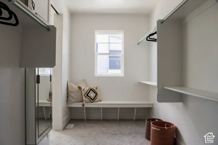 Recessed window, built-in bench with integrated shelving, white built-in shelving, and hanging rods