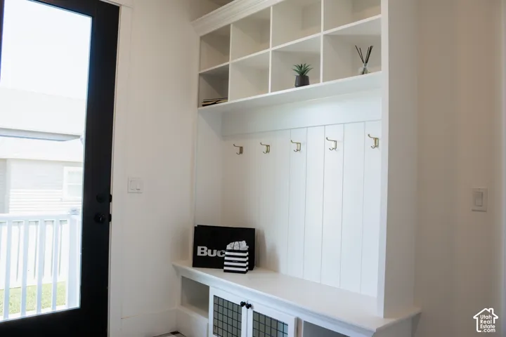 Built-in storage unit featuring open shelving, coat hooks, and lower cabinetry with glass panel inserts