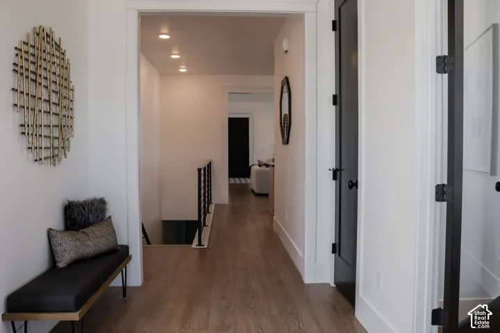 Hardwood-look flooring, recessed ceiling lighting, white trim, and black interior doors