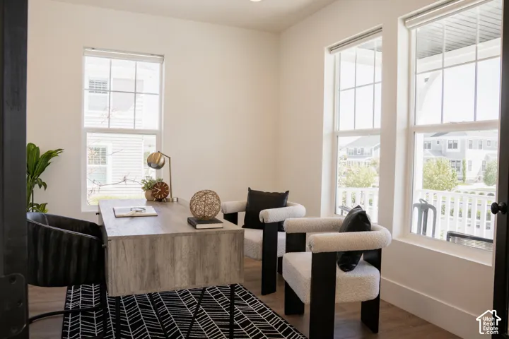 Bright interior featuring three large windows, white walls, and wood-finish flooring