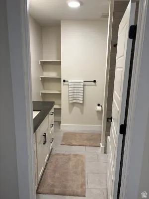 Vanity with dark countertop, white cabinetry, and matte black hardware