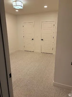 Plush carpeting, two paneled doors with black hardware, recessed lighting, and a semi-flush mount fixture