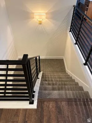 Modern horizontal black metal railings with wood-finish flooring and wall-mounted sconce lighting