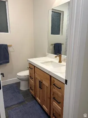 Spacious vanity with a white countertop and wood-finish cabinetry, featuring a rectangular sink and bronze-finish faucet
