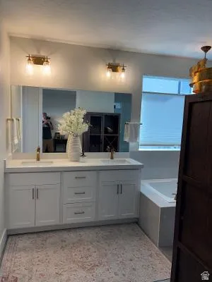 Dual vanity with white cabinetry, integrated sinks, and brass-finish fixtures