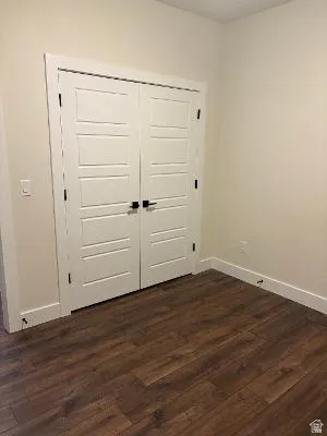 White paneled bifold doors with matte black hardware, wood-finish flooring, and white baseboards