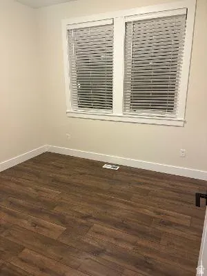 Wood-finish plank flooring, white baseboards, and neutral wall paint