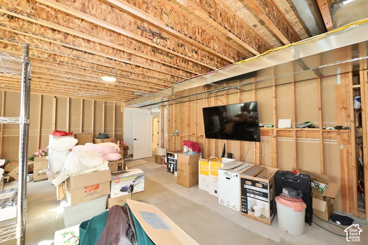 Unfinished interior space featuring exposed wood-stud wall framing, exposed joist ceiling, concrete flooring, and metal HVAC ductwork
