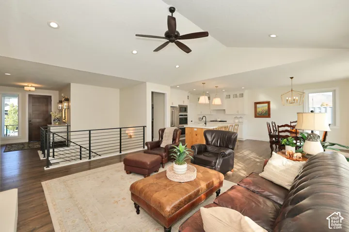 Vaulted ceilings, wood-finish flooring, recessed lighting, and a metal horizontal-bar staircase railing
