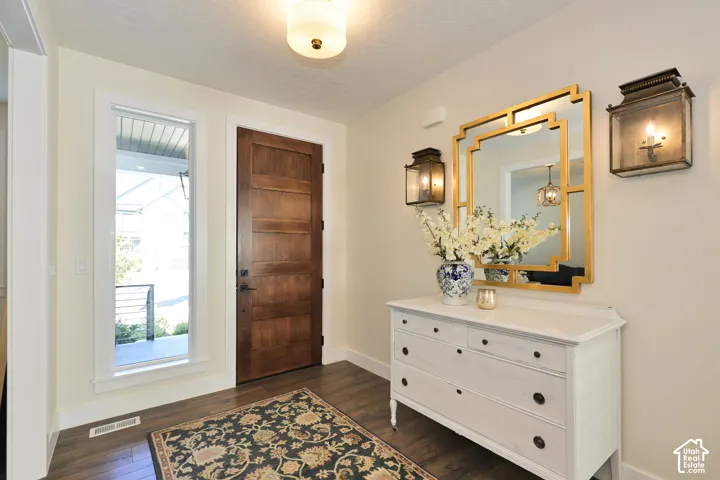 Foyer featuring a dark-stained wood entry door, wood-finish flooring, full-length sidelight window, and dual antique-style wall lanterns