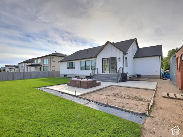 Vertical board-and-batten exterior siding, concrete patio, lawn, and wood-finish privacy fencing