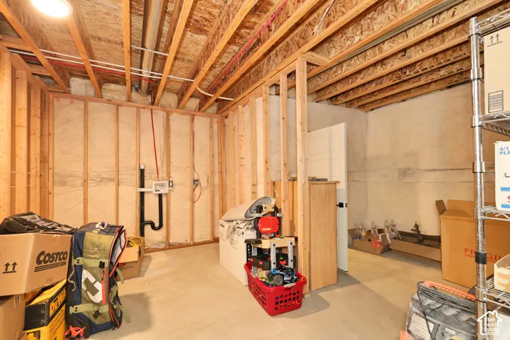 Unfinished lower level featuring exposed wood framing, concrete foundation walls, fiberglass insulation, and exposed ceiling joists