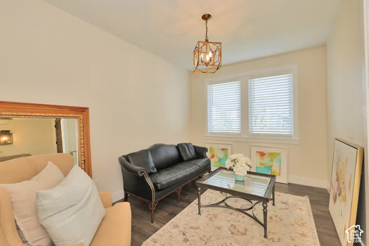 Room featuring wood-finish flooring, dual windows with horizontal blinds, and a geometric metal pendant light fixture