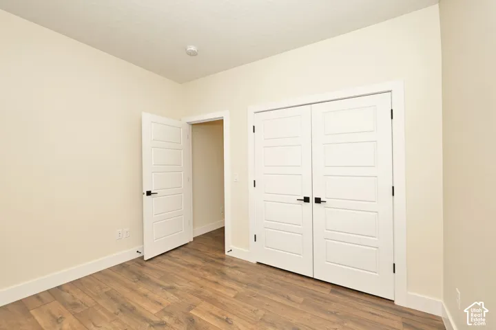 Room featuring wood-finish flooring, white five-panel interior doors, and matte black door hardware