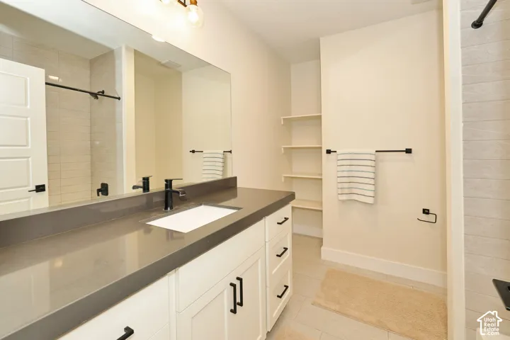 White vanity featuring a solid-surface countertop, rectangular undermount sink, matte black hardware, built-in shelving, and a full-width vanity mirror