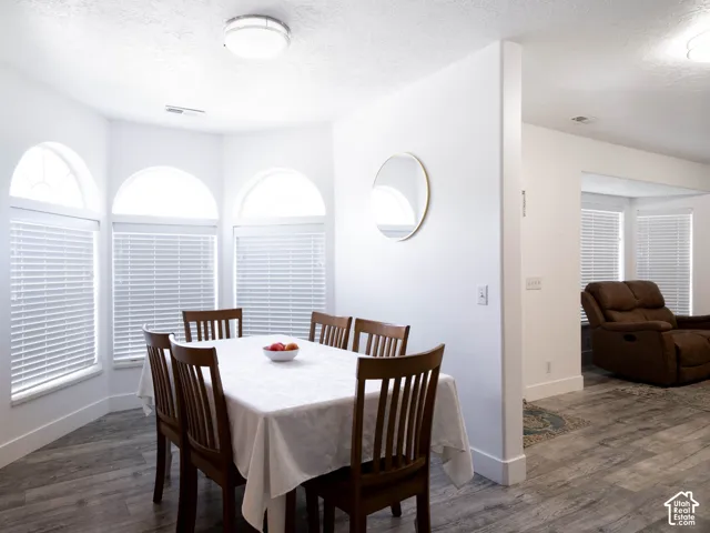 Dining area featuring a bay window with arched transom windows and horizontal blinds, wood-finish flooring, and recessed lighting