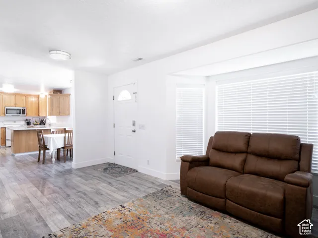 Open-concept living space featuring wood-finish flooring, white walls, and a bay window