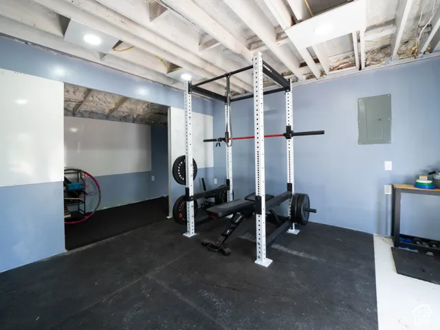 Exposed ceiling joists with recessed lighting, two-tone wall treatment, and durable rubber flooring