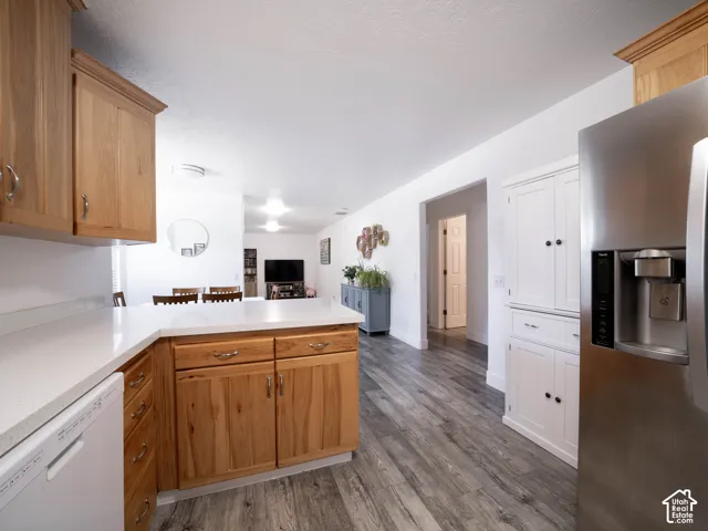 Kitchen with light wood-finish cabinetry, white countertops, a stainless steel refrigerator, and wood-look flooring