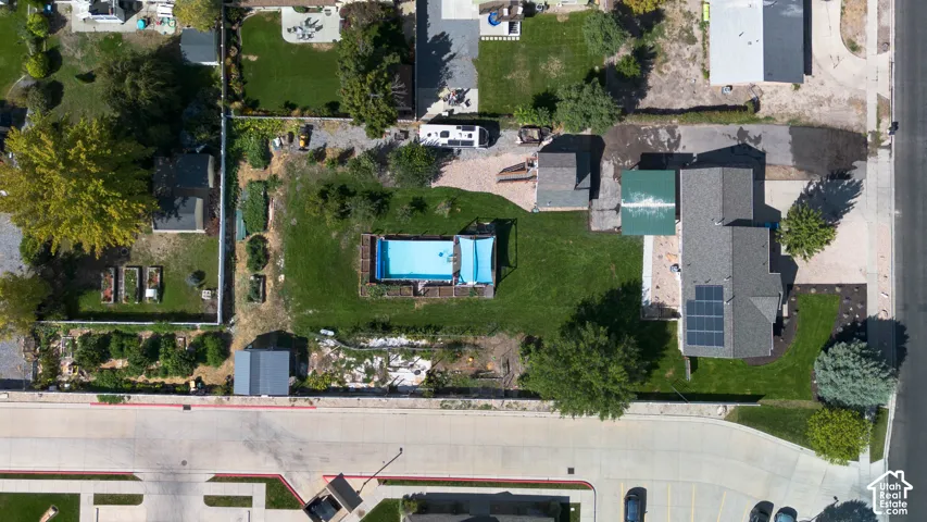 Expansive property featuring an in-ground swimming pool, multiple garden beds, a dedicated patio area, and a well-maintained lawn