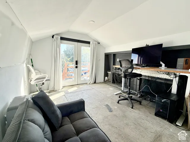 Vaulted ceiling with recessed lighting, double French doors, and built-in shelving
