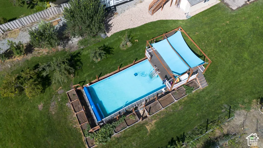Expansive backyard featuring an in-ground swimming pool, a multi-level wood deck, and a shade canopy