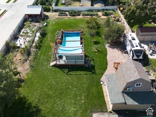 Expansive green lawn, above-ground pool with surrounding deck, gravel-covered side yard, a separate office/gym structure with a gable roof