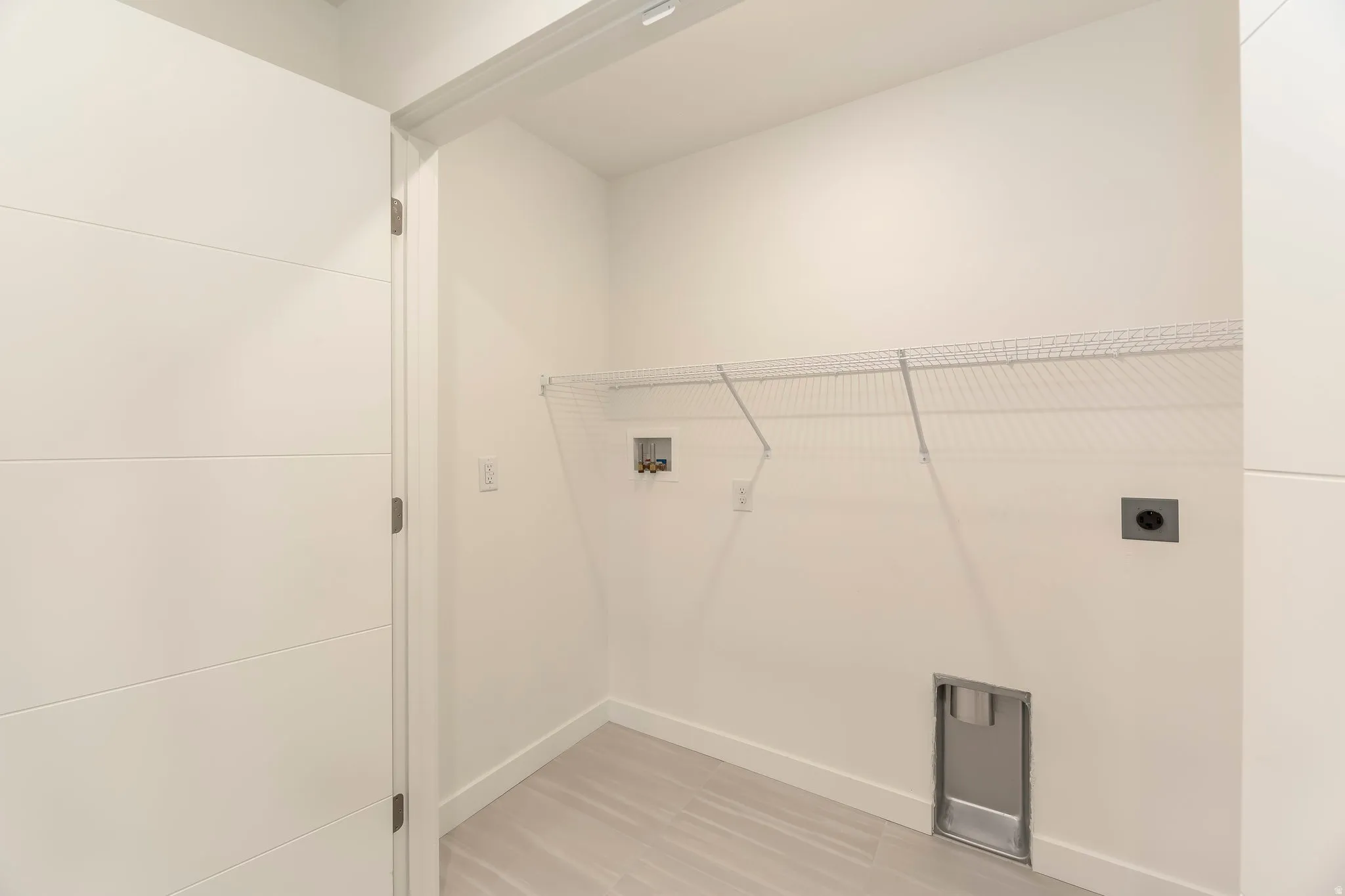 White wire shelving, light-colored tile flooring, flush-panel interior door, and clean white walls